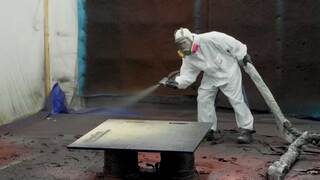 Employee using paint sprayer in Facility
