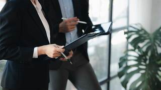 two people in business attire reviewing paperwork in an office
