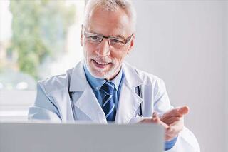 doctor in lab coat conducting telehealth appointment on the computer