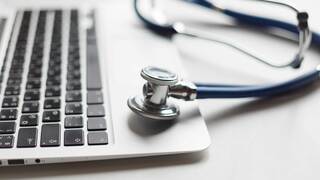 laptop with stethoscope sitting on a desk